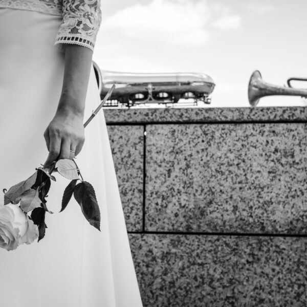 La main d'une mariée à Strasbourg en Alsace qui tient une rose blanche devant des instruments de musique