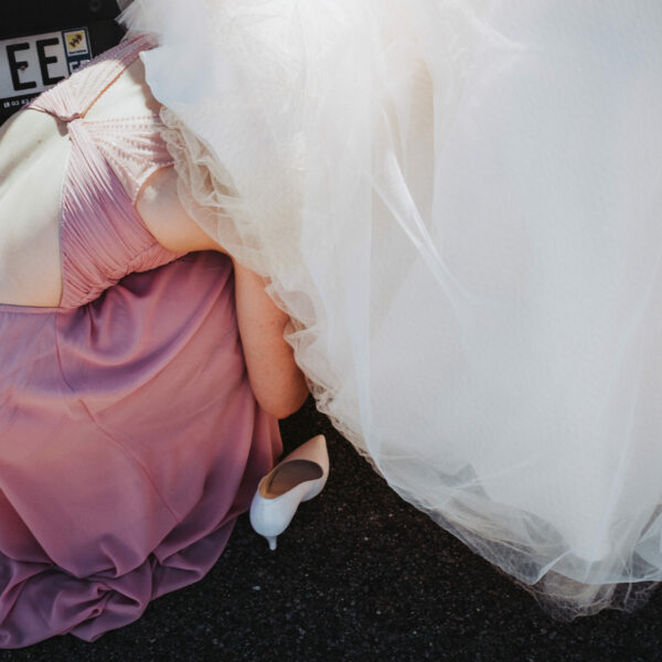 Une demoiselle d'honneur qui enlève les chaussures de la mariée sous sa robe après la cérémonie à l'église, en Haute-Saône.