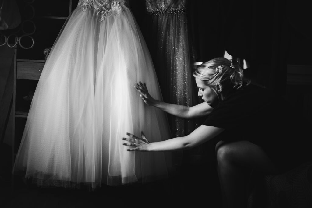 Une mariée qui passe les mains sur sa robe de mariage avant de l'enfiler.