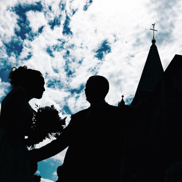 Mariés qui posent sous le ciel devant une église en Haute-Saône.