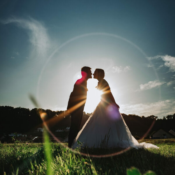 Deux mariés qui s'embrassent au coucher de soleil dans un champs, en Franche-Comté