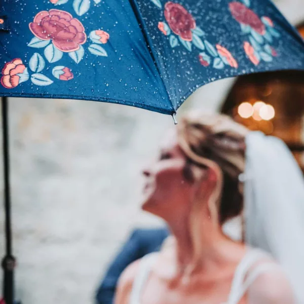 Mariée qui sort de l'église derrière un parapluie le jour de son mariage dans le Doubs.